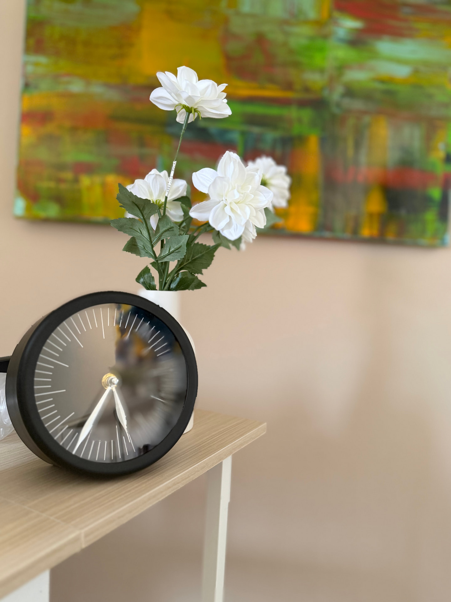 Uhr und weiße Blumen vor einem farbenfrohen Bild